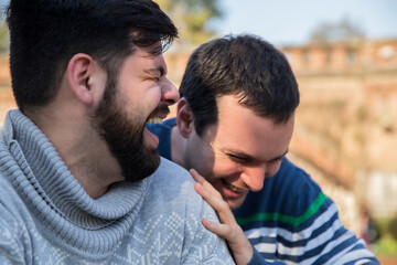 Happy gay couple in love sharing laughs outdoors