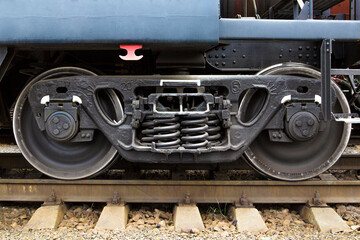 A railway bogie on the rails. Side view of railroad car undercarriage showing wheels and springs.