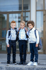 Three schoolboy friends are hugging next to the school