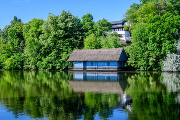 Obraz premium Landscape with old wooden house on Herastrau lake and large green trees in King Michael I Park (former Herastrau) in Bucharest, Romania, in a sunny autumn day.