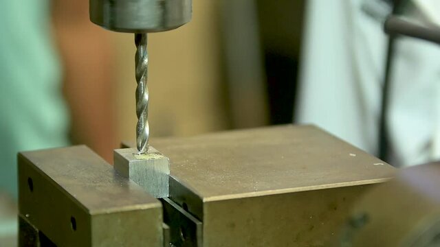 Taladro de mesa haciendo un hueco en un bloque de metal