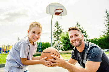 Happy basketball family portrait play this sport on summer season. The father play with boy