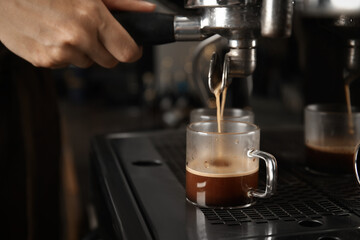 Barista making espresso using professional coffee machine, closeup