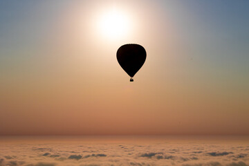 Hot air ballon over the cloud during sunset. Scenic view above the clouds