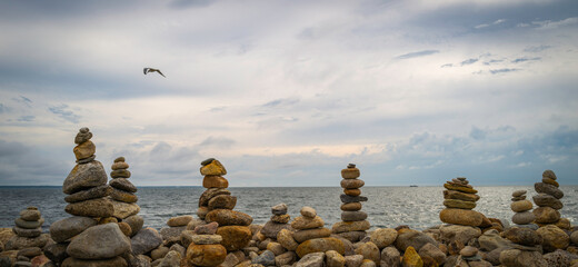 Tranquil seascape with Zen-like rock pikes on the beach with a seagull flying in the dramatic cloudy sky at Dawn.