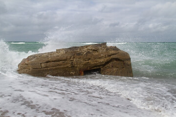 Waves splash against a German bunker from the second world war, fallen from te dunes in the sea in the Tannis Bugt in Denmark