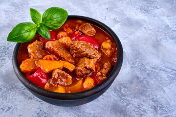 Traditional Hungarian hot goulash soup on grunge background.