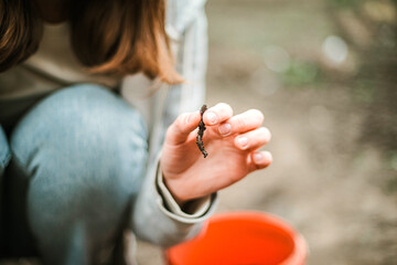 Woman holding  earthworm in a garden.