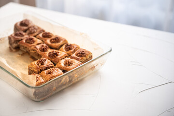 baklava pie with walnuts in a glass baking dish. A few pieces are already missing in the form.