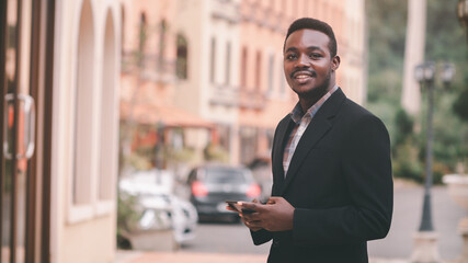 African businessman in suits use mobile phones happily in the city.Business and technology concept