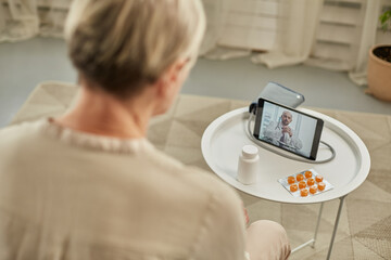 An elderly woman communicates remotely via a tablet with her doctor. Telemedicine concept