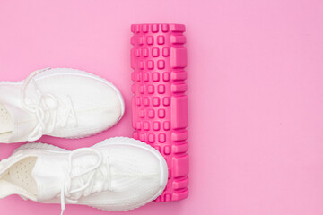 The concept of fitness. Pink fitness roller for training. Sneakers. Women's fitness at home.