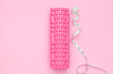 The concept of fitness. Pink fitness roller for training. Centimeter tape. Weight loss. Women's fitness at home.