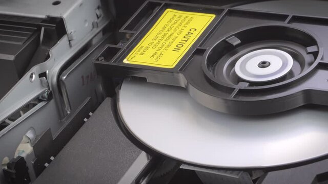 Closeup shot of a dvd being inserted into a dvd player. Showing the process from the inside.