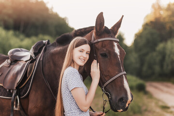 Fototapeta premium Portrait of young girl standing next to a horse looking at camera smiling.