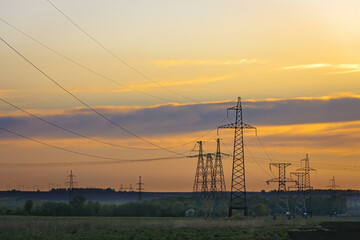 Transmission tower at sunset. Electric transmission station with metal poles and electrical wires