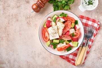 Radish, cucumber, tomato, pepper and feta cheese with spices pepper and olive oil in white bowl on grey slate, stone or concrete background. Healthy food concept. Top view.