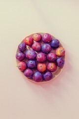 In the center, on a light pink background, there is a homemade plum in a wooden bowl