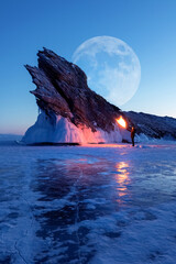 Winter Siberian landscape. Lake baikal, silhouette of a man with a torch on the background of the...