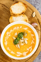 Pumpkin cream soup with seeds on a stone background, with copy space. Top view