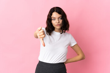 Teenager Ukrainian girl isolated on pink background showing thumb down with negative expression