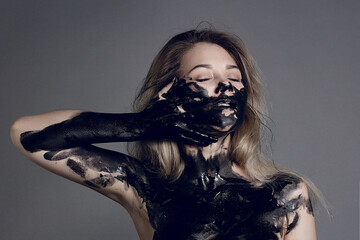 Beauty provocation. Body painting project. Portrait of a young woman with black oil pouring....