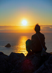 Chica joven disfrutando de la puesta de sol en el cabo de Finisterre