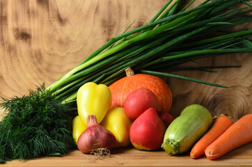 Pumpkin, tomatoes, onions, zucchini, bell pepper, carrots and dill on a wooden background.