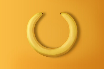 Creative banana wreath on yellow background with copy space. Top view.