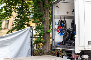 Fototapeta na wymiar Open cargo box of filming movie set production equipment transport truck van vehicle with many electrical cables wire, rack and sockets on city streey outdoors. Cinema or television supply rental car