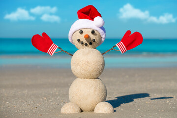Snowman on the beach. Sandy Christmas snowman in red Santa hat and mittens or gloves. Smiley...