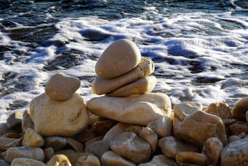 Stacked pebbles in front of foamy sea surface