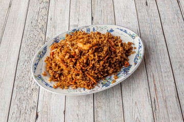 Recipe of fried Peruvian chaufa rice with wok vegetables and prawns with soy sauce on light wooden table