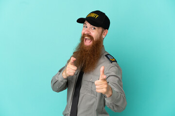 Redhead security man isolated on white background pointing to the front and smiling