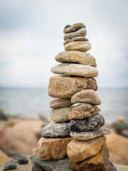 Piles of stones on the rocky beach with blurry sea background
