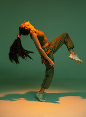 Dancing athletic mixed race girl performing expressive fiery hip hop or ethnic afro dance in studio...