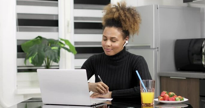Afro american woman wearing headphones studying online from home watching web class lesson or listening tutor by video call elearning on pandemic isolation. Remote education.