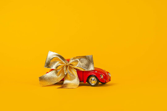 Miniature Red Car Under A Golden Bow Is A Gift For February 14, Christmas. Minimal Concept. Raffle. Lottery -27.09.2020, Moscow, Russia.