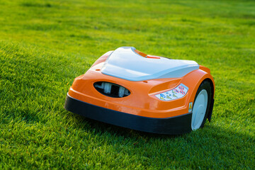 Automatic lawn robot mower moves on the grass slope, lawn. Close up side view - obrazy, fototapety, plakaty