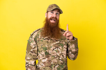 Military Redhead man over isolated on yellow background thinking an idea pointing the finger up