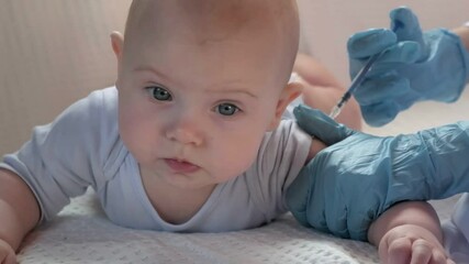 Pediatrician vaccinating newborn baby. Vaccine, Vaccination for infant child Soft focus Syringe in hands of a nurse and blurred background of infant baby on white. Doctor in blue gloves, close up.