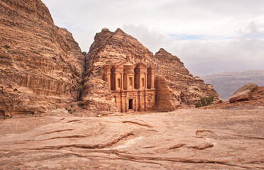 Ad Deir - Monastery - ruins carved in rocky wall at Petra Jordan, mountainous terrain with overcast sky background