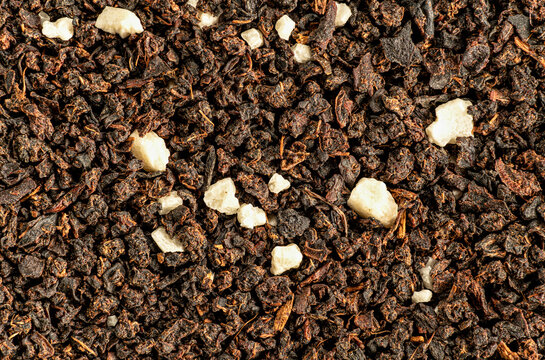 Brown flakes of black loose leaf tea from bags - Earl grey variety. White crystals are artificial flavouring 1.5x magnification, image width 23mm