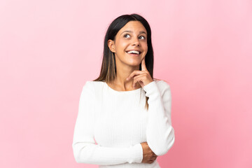 Caucasian girl isolated on pink background thinking an idea while looking up