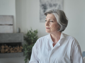 Fototapeta premium A confident, educated older lady executive manager stands in a bright contemporary workplace and appearing serious. A senior female professor or instructor headshot in university