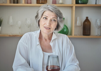 Portrait of a happy senior elderly woman with glass of wine in a bright comfortable apartment. Close up smiling beautiful retired grandmother in kitchen.