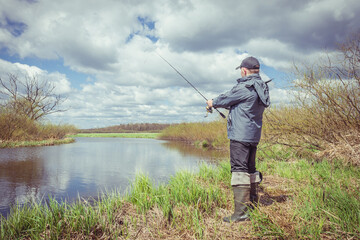 Fisherman throws spinning rod on the river bank.