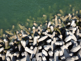 Sea meeting breakwater made out of dolos blocks. Aerial view. Abstract. Pattern. Copy space for text - obrazy, fototapety, plakaty