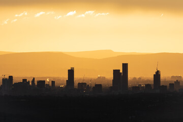 Manchester city skyline silhouetted against the sunrise, the tower blocks and buildings are visible against the yellow morning glow