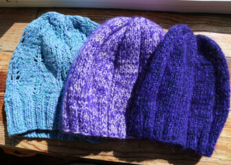 violet  woolen  hats, made of cable knitted fabric. texture knitted headpiece, warm  handmade fabric closeup vertical. Blue and purple beanie hats